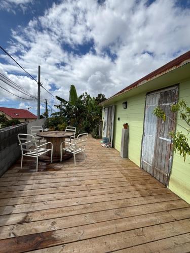een houten terras met een tafel en stoelen op een huis bij Location l'îlot tropical in Le Bois de Nèfles