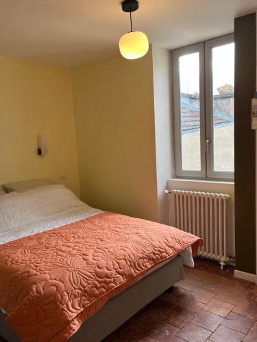 a bedroom with a bed and a window at Le Petit Logis in Marcigny
