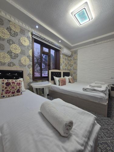 een hotelkamer met twee bedden en een raam bij HOTELVAZIRA in Samarkand