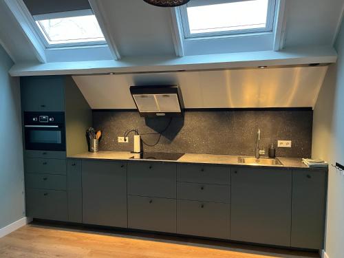 een keuken met een spoelbak en twee ramen bij Hei-d-Away in Otterlo