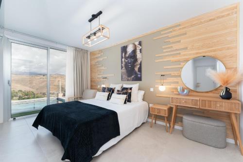 a bedroom with a bed and a desk and a mirror at Villa Trilux, Infinity Pool, Jacuzzi, BBQ in Salobre
