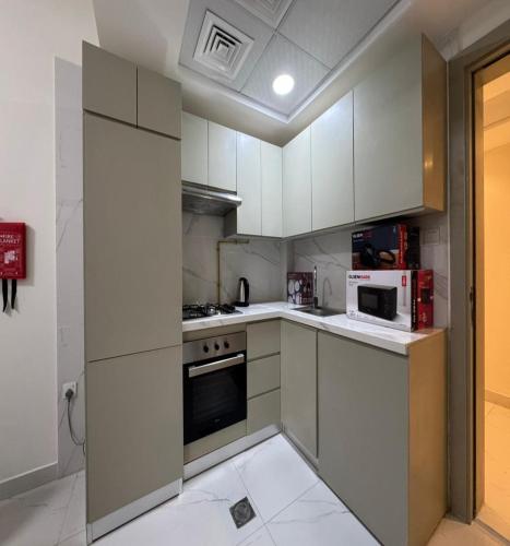 a kitchen with white cabinets and white appliances at Luxury Apartment with Pool Gym & Free Parking at Equiti Gates Jebel Ali in Dubai