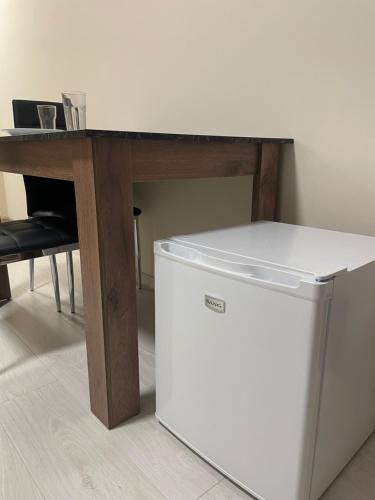 a white refrigerator under a table with a desk at Mini House Shumen in Shumen