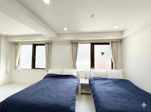due letti in una stanza con finestre di Hotel LEAP ad Osaka