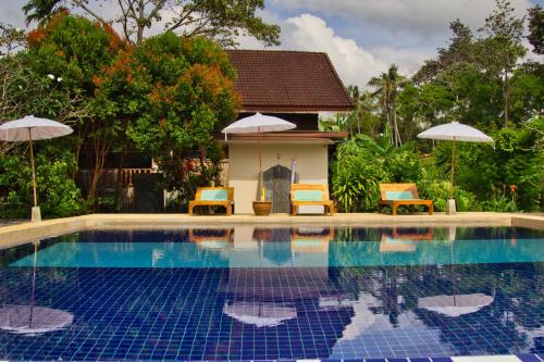 een zwembad met stoelen en parasols naast een huis bij Lanta White Rock Resort in Koh Lanta