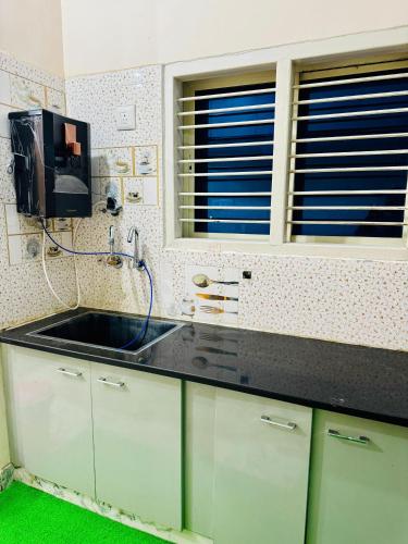 eine Küche mit einem Waschbecken und einem TV an der Wand in der Unterkunft Flats in city center, next to NEXUS MALL in Mysore