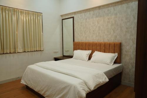 a bedroom with a large bed with white sheets and a mirror at Salt Water Sanctuary in Diveagar