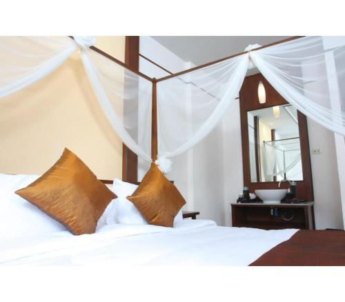 a bedroom with a bed with white sheets and a mirror at Palette Bangkok Natural Resort and Spa in Bangkok