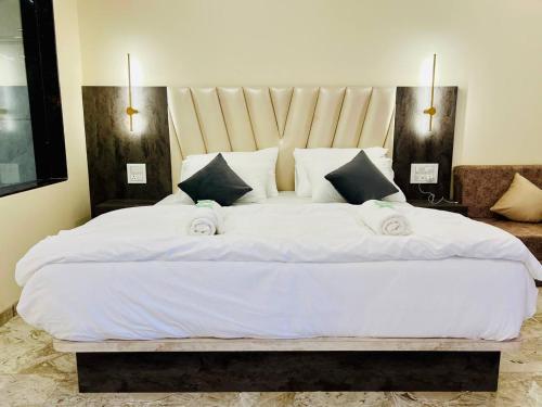 a bedroom with a large bed with white sheets and pillows at ARANYAM By StarGlaze Retreat in Mahabaleshwar
