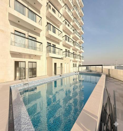 a swimming pool in front of a building at Luxury Apartment with Pool Gym & Free Parking at Equiti Gates Jebel Ali in Dubai