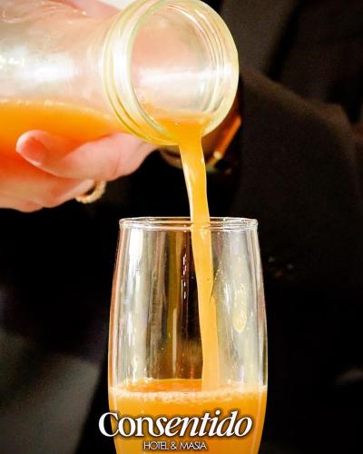 una persona che versa del succo d'arancia da una bottiglia in un bicchiere di Hotel Consentido a Granollers