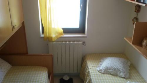Habitación pequeña con 2 camas y ventana en La Montanara Apartment en Castel di Sangro
