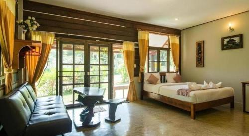 une chambre avec un lit et un canapé dans une pièce dans l'établissement De Bua Valley, à Ban Kom