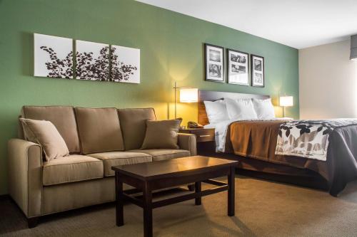 a hotel room with a bed and a couch at Sleep Inn & Suites East Syracuse in East Syracuse