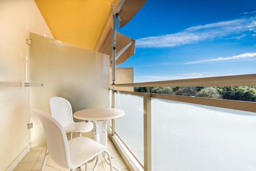 a balcony with white chairs and a table at Hotel Garden Istra Plava Laguna in Umag