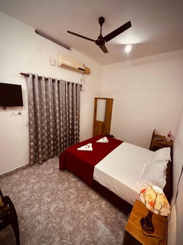 a bedroom with a bed and a ceiling fan at The Beach Hive in Varkala
