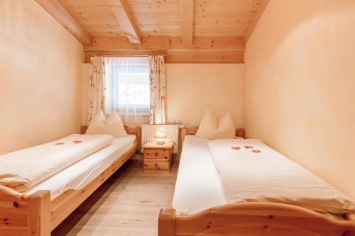 two beds in a small room with a window at Alimonte Romantic Appartements in Sankt Johann in Tirol