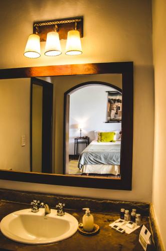a bathroom with a sink and a mirror with a bed at Viñas De Cafayate Wine Resort in Cafayate