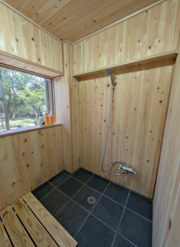a bathroom with a shower in a wooden wall at Kaido Nomad CoLiving in Yuzawa