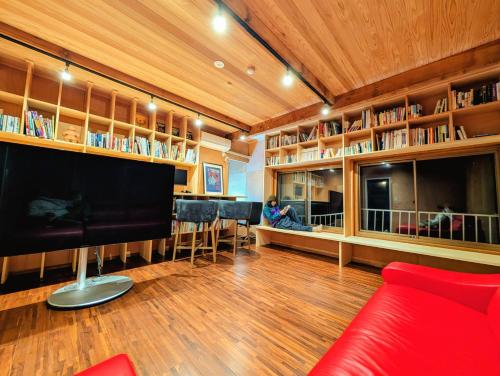 een woonkamer met een rode bank en boekenplanken bij Kaido Nomad CoLiving in Yuzawa