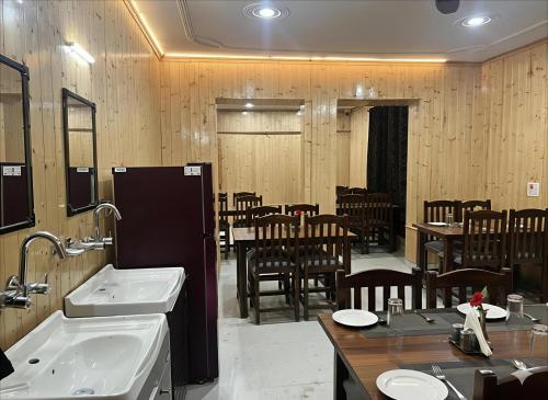 a restaurant with two sinks and a tables and chairs at The Routes Pahalgam in Kolur
