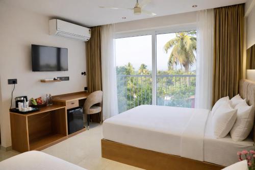 a hotel room with a bed and a desk and a window at Hotel Hanata Kochi in Cochin