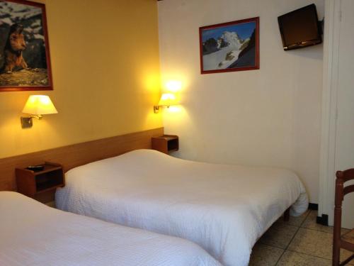 a hotel room with two beds and a tv at Hotel Sandra in Vizille