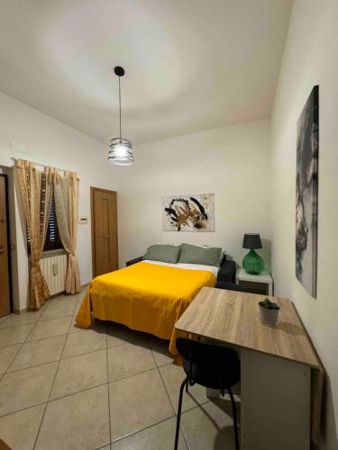 a bedroom with a yellow bed and a table at Bilocale di Charme in Baronissi