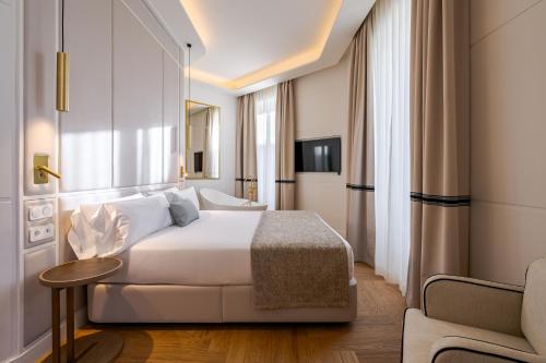ein Hotelzimmer mit einem weißen Bett und einem Stuhl in der Unterkunft La Fonda de los Principes in Madrid