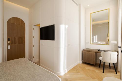 ein Schlafzimmer mit Kühlschrank, Schreibtisch und Spiegel in der Unterkunft La Fonda de los Principes in Madrid