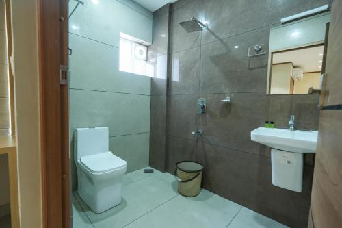 a bathroom with a toilet and a sink and a shower at Rasha Suites in Kalpetta