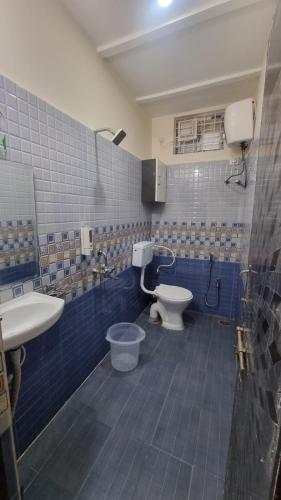 a blue tiled bathroom with a toilet and a sink at Kutir Stay Aaram in Secunderabad