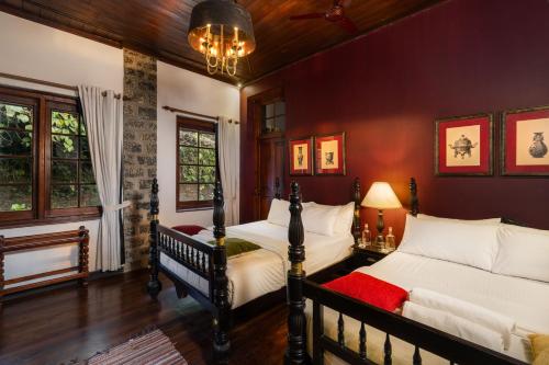 two beds in a bedroom with red walls at Garfield Bungalow by TONIK - 4BR Private Bungalow in Haputale - Mountain Views in Haputale