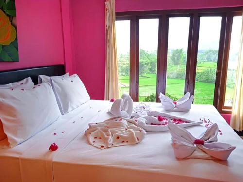 een roze slaapkamer met een wit bed waarop eten ligt bij FX 72 Ruteng Hotel in Ruteng