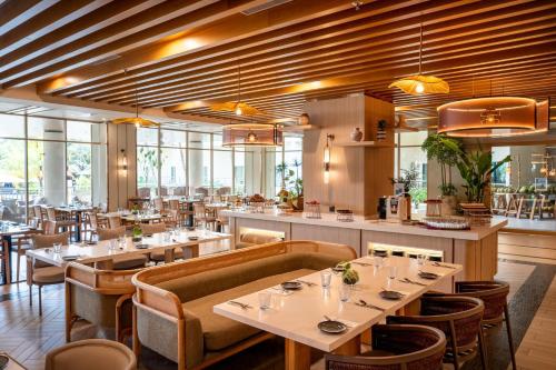 een restaurant met tafels, stoelen en ramen bij Swiss-Grand Beach Resort Kuantan in Kuantan