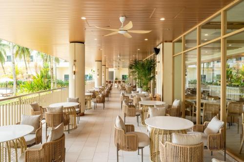 een restaurant met tafels, stoelen en ramen bij Swiss-Grand Beach Resort Kuantan in Kuantan