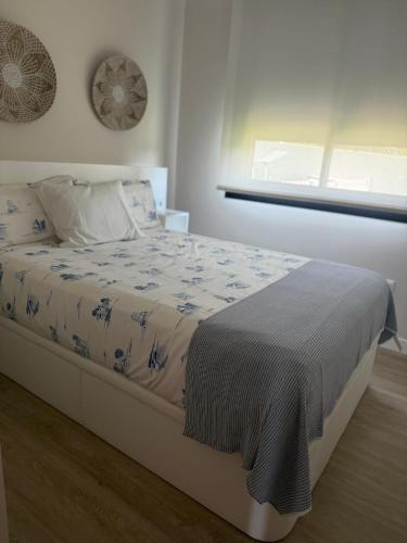 a bed in a white bedroom with a window at Lagarteira in Sanxenxo