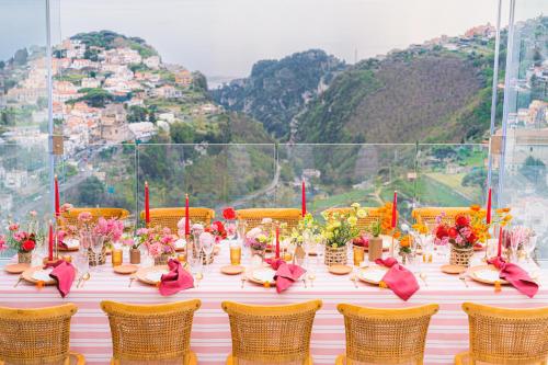 een tafel met stoelen en bloemen bovenop een berg bij Monte Brusara Relais in Ravello