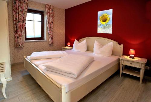 a bedroom with a large white bed with a red wall at Villa Rosamunde in Burg