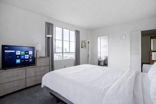 a white bedroom with a large bed and a flat screen tv at Spacious 2 Bedroom 2 Bathroom Unit Great Location in Los Angeles