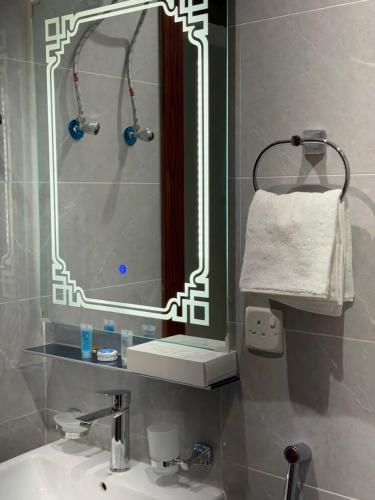 een badkamer met een wastafel met een spiegel en een handdoek bij ركن صحاري للشقق المخدومة ضبا Rukn Sahari for Served Apartments in Ḑubā