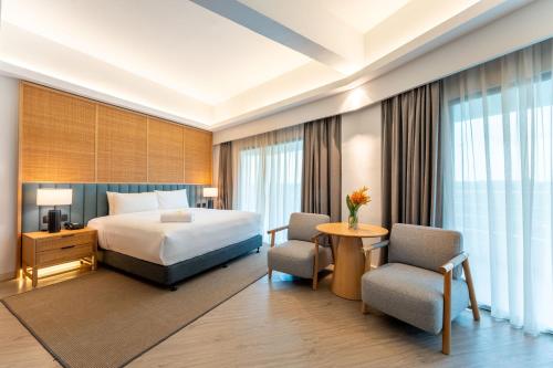 een hotelkamer met een bed en twee stoelen bij Swiss-Grand Beach Resort Kuantan in Kuantan