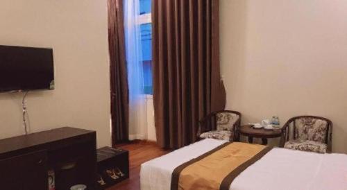 ein Hotelzimmer mit einem Bett und zwei Stühlen und einem Fernseher in der Unterkunft LUCKY STAR HOTEL in Buon Ma Thuot