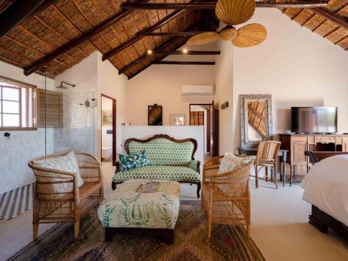 a bedroom with a bed and chairs and a table at Yellowtail Finca in Plettenberg Bay