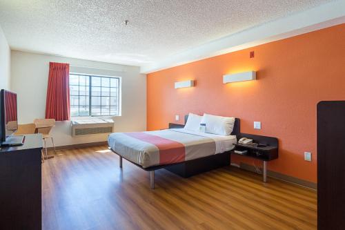 a hotel room with a bed with an orange wall at Motel 6-Williams, AZ - West - Grand Canyon in Williams