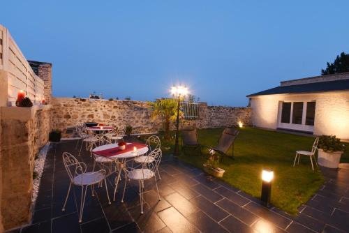 een patio met een tafel en stoelen en een gazon bij Le Clos Saint Martin in Laon
