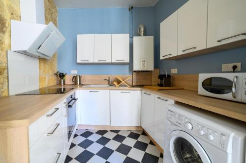 a kitchen with white cabinets and a checkered floor at Votre famille à Périgueux Charme & Confort in Périgueux