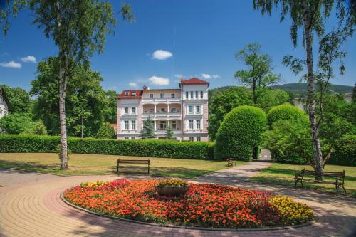 a large building with a flower garden in front of it at Willa Arabeska in Lądek-Zdrój