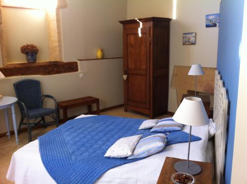 - une chambre avec un lit doté d'une couverture bleue et d'oreillers dans l'établissement La Relinquiere, à Milhac
