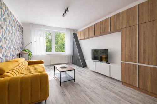 a living room with a yellow couch and a tv at Comfort 18 Real Family Home in Miskolc